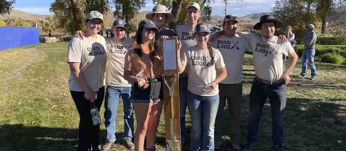 A group of students holding a shovel and an award.